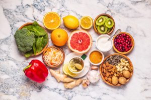 A Natural Guide to Better Health AdedejiOfAkure Media Assortment of fresh fruits vegetables nuts and seeds arranged on a marble surface including citrus halves kiwi broccoli greens red pepper yogurt and bowls of nuts and seeds